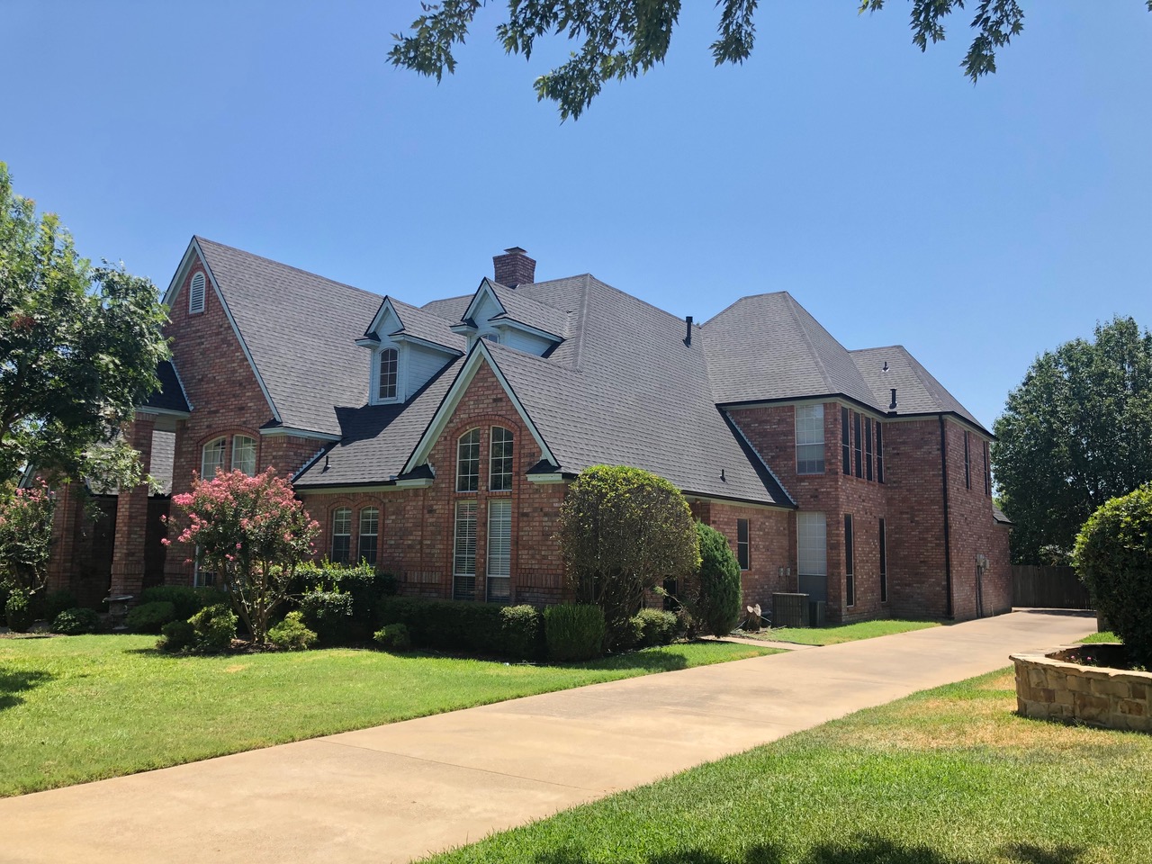 Large brick house with newly installed dark shingle roof